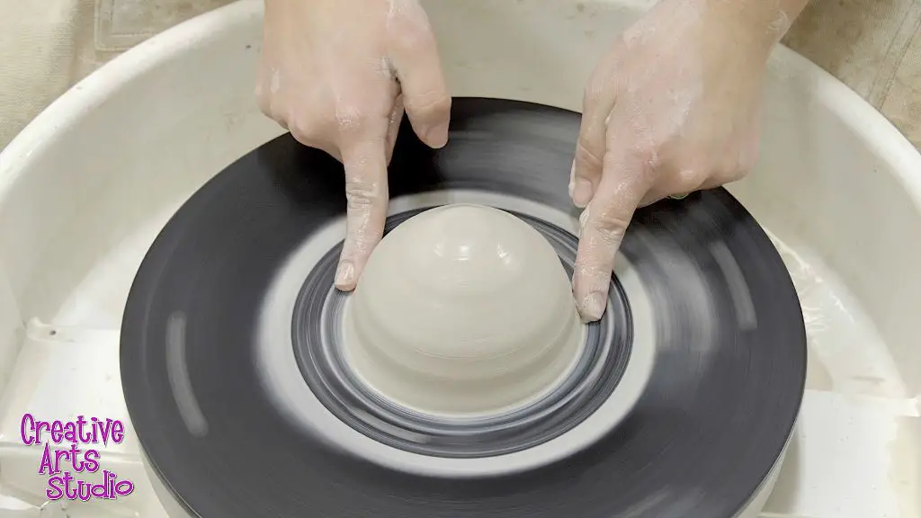 a beginner practicing centering clay on a pottery wheel