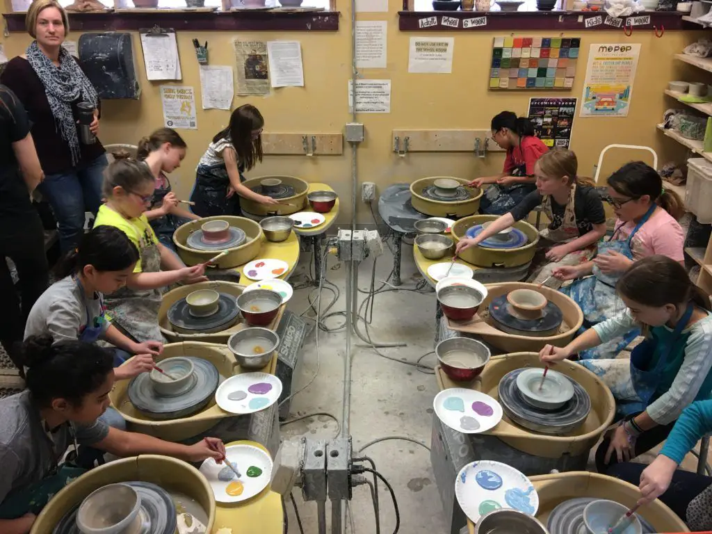 a ceramic artist throwing a pot on a wheel in their studio.