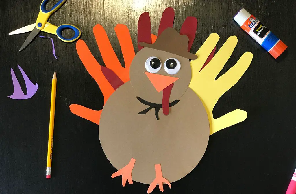 a child decorating a hand turkey craft