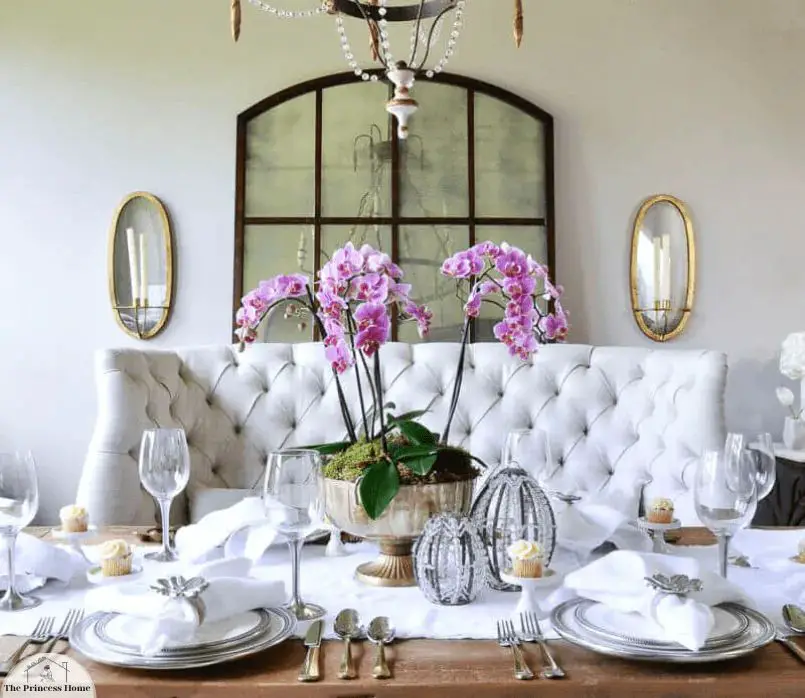 a dining table styled with decorative pieces like flowers, fruit, greenery, candles, vases, and other accents to create a warm, inviting mood while dining.