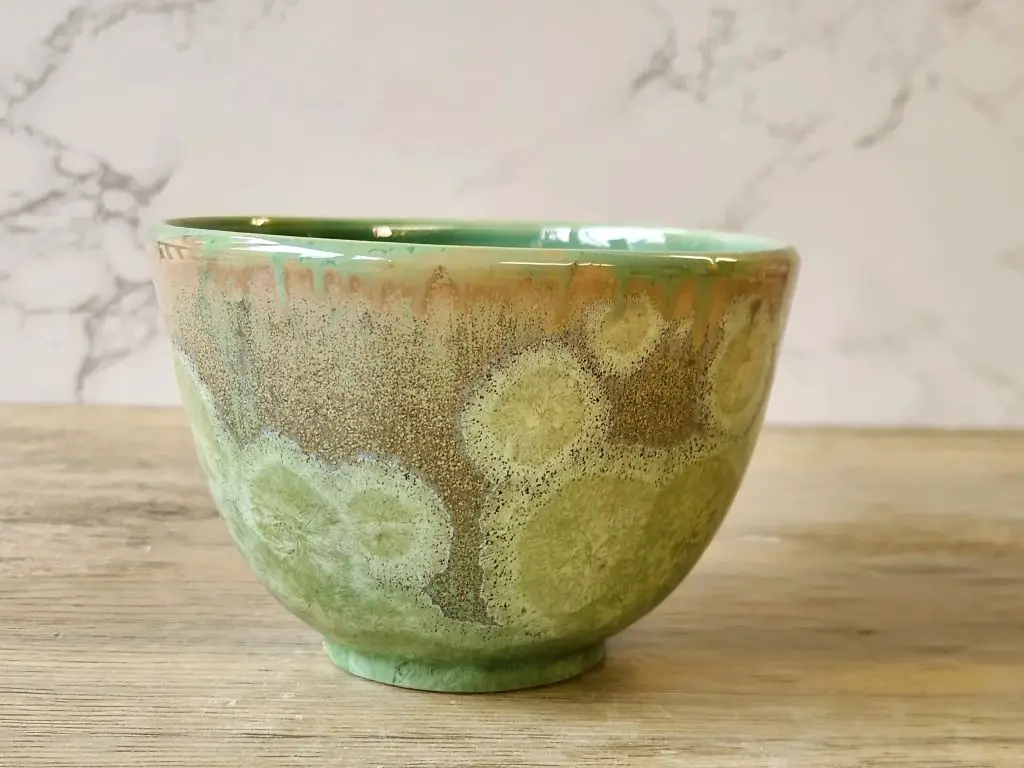 a green bowl with shimmering crystalline glaze