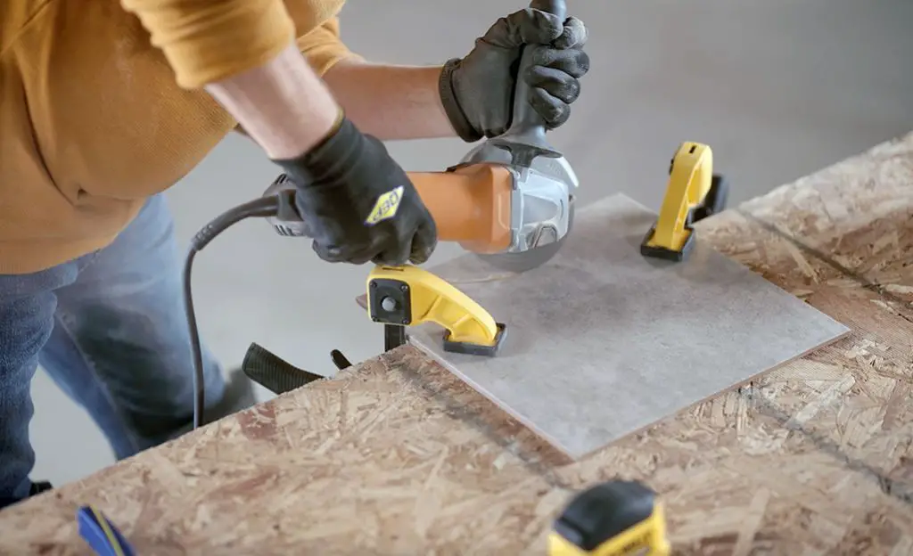 a home depot employee operating a tile saw to cut ceramic floor tiles for a customer.