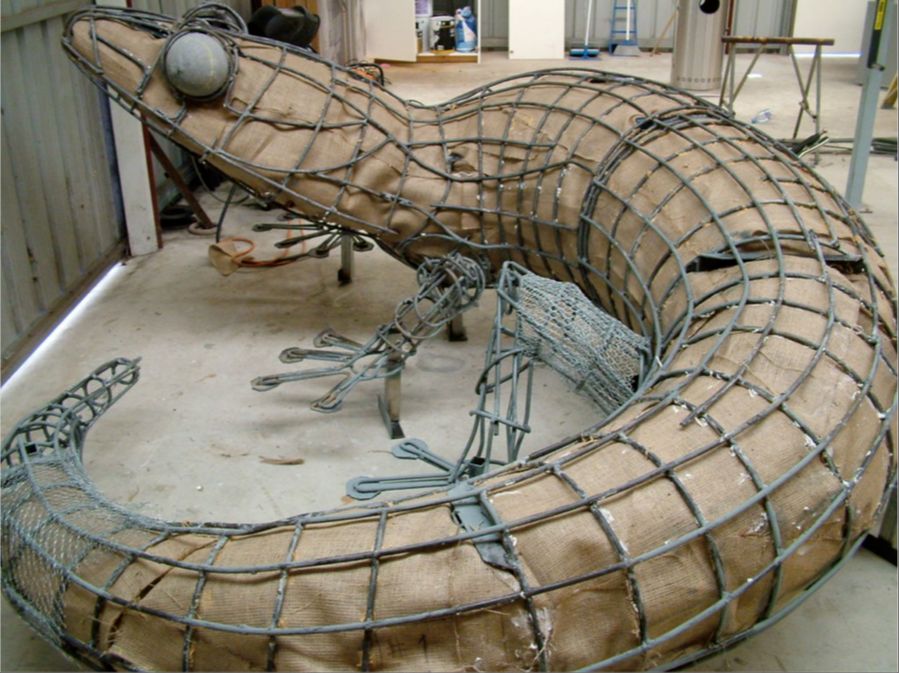 a large clay sculpture being supported by an internal wire armature frame during the creation process