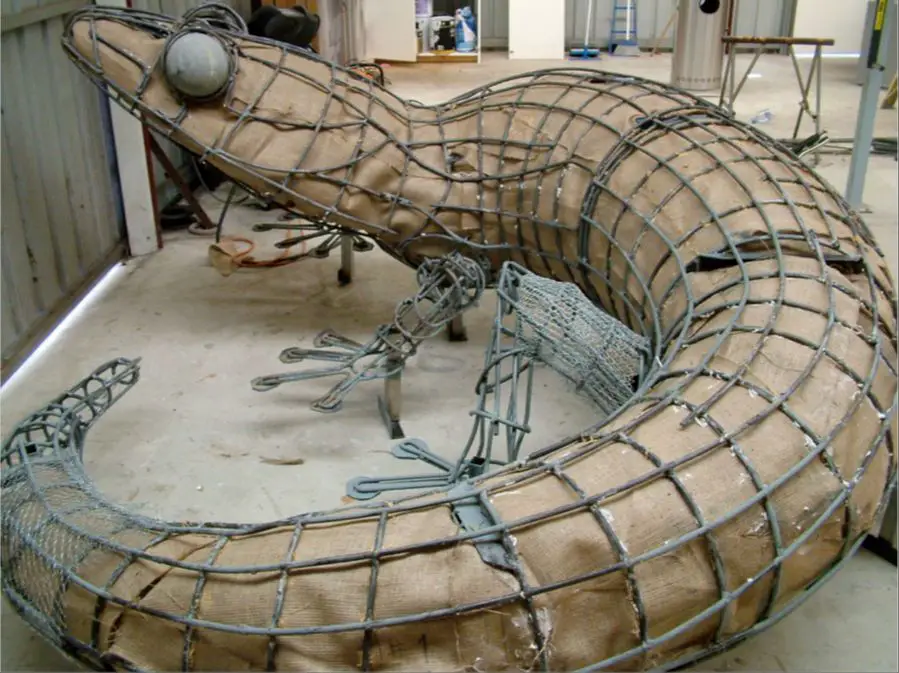 a large clay sculpture being supported by an internal wire armature frame during the creation process