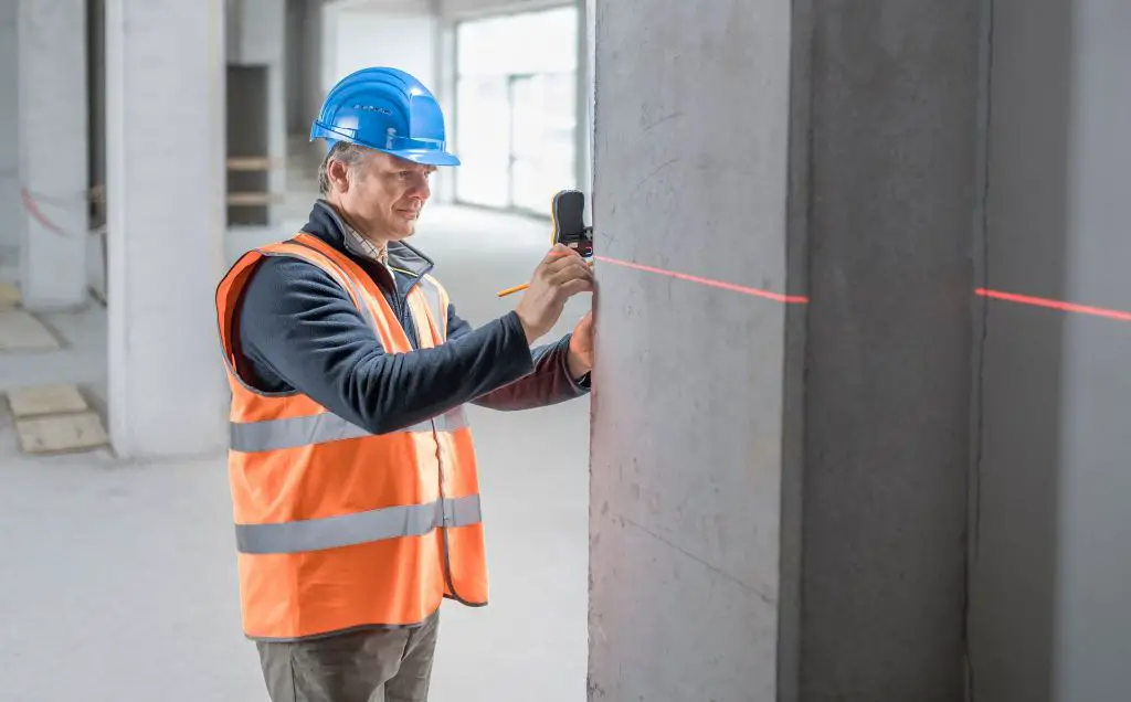 a man using a laser level to ensure shelf brackets are properly positioned and level