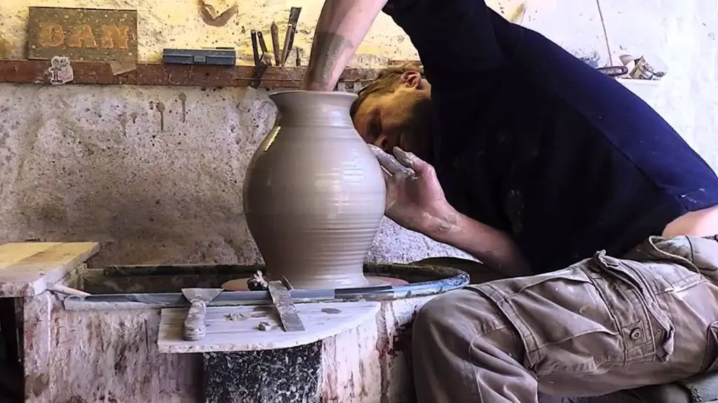 a person demonstrating how to throw a clay vase on a pottery wheel.