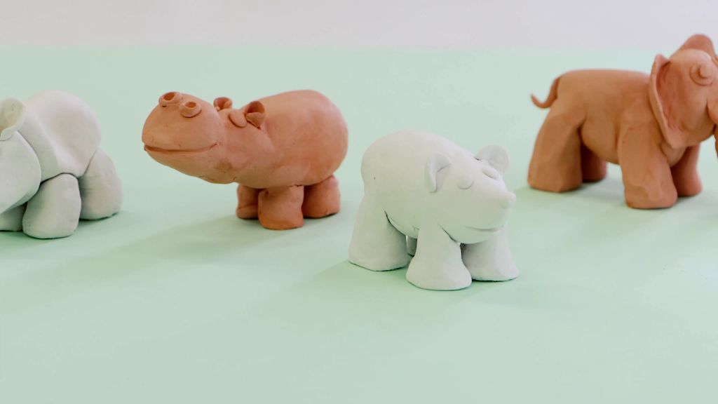 a person sculpting an animal figurine out of white air dry foam clay.