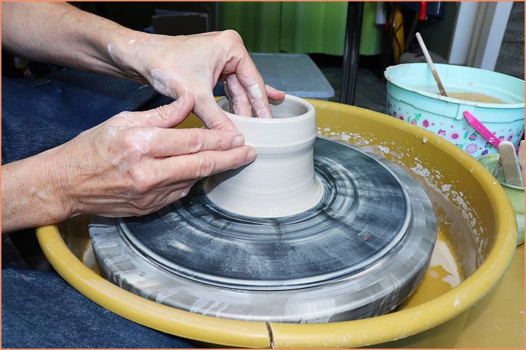a person using a pottery wheel to throw and shape clay into a smooth rounded form