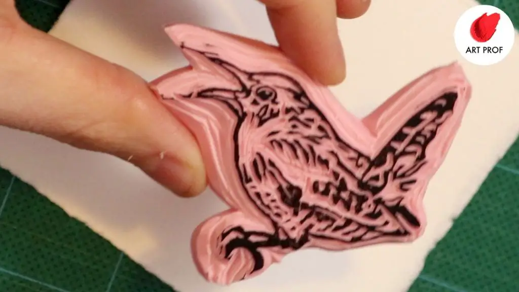 a person using a rubber stamp on a small clay sculpture.