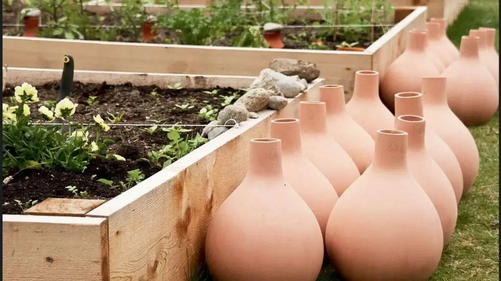 a person watering a clay planter outdoors.