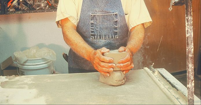 a person wedging a ball of clay on a table