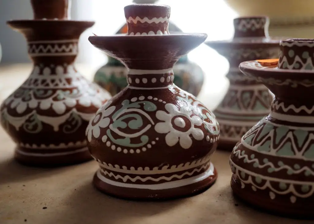 a photo showing examples of slip trailing decoration on pottery pieces. the slip forms delicate raised lines and dots against the contrasting clay body.