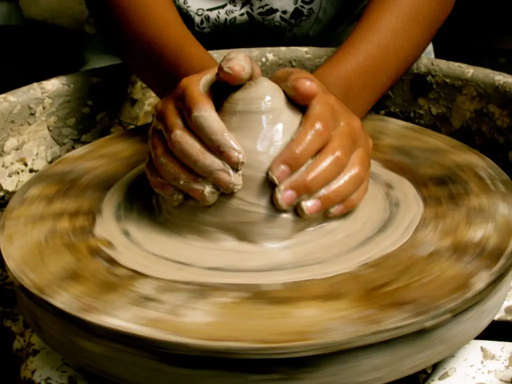 a potter forming a clay pot on a spinning pottery wheel in a studio workshop