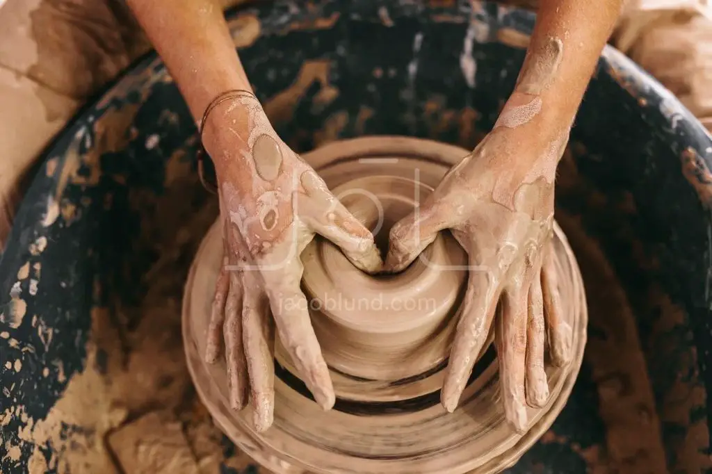 a potter shapes clay on a pottery wheel