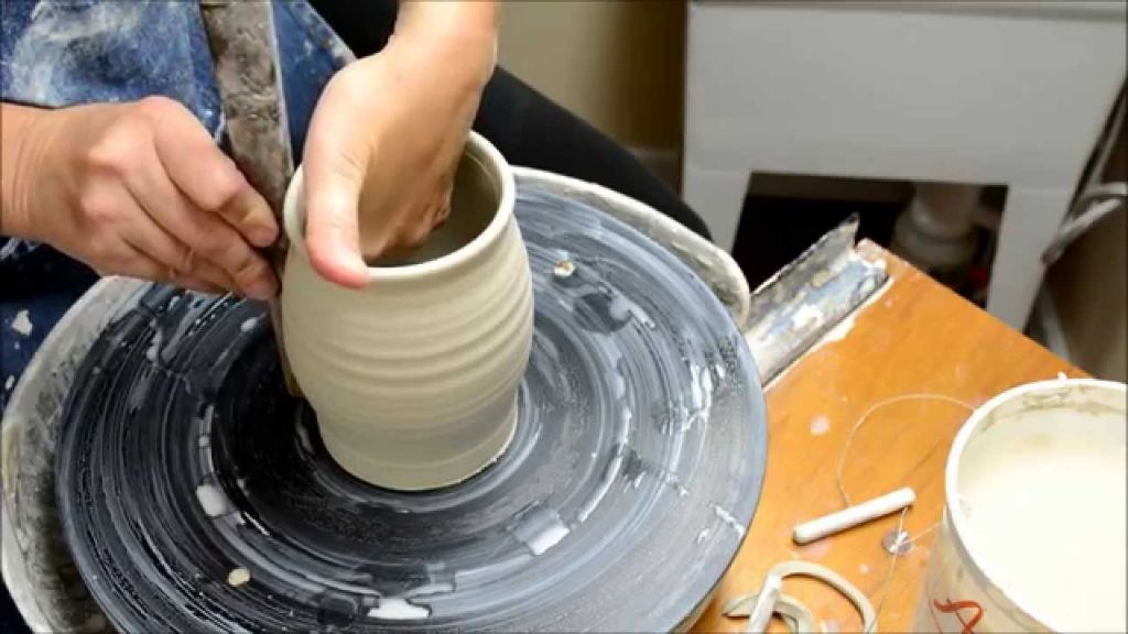 a potter shaping clay on a pottery wheel.