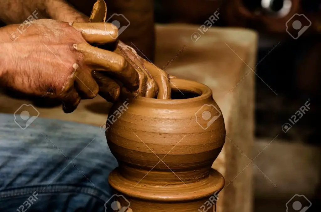 a potter shaping clay on a pottery wheel.