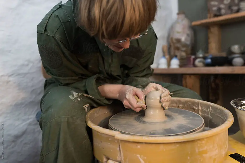 a potter shaping clay on a rotating pottery wheel