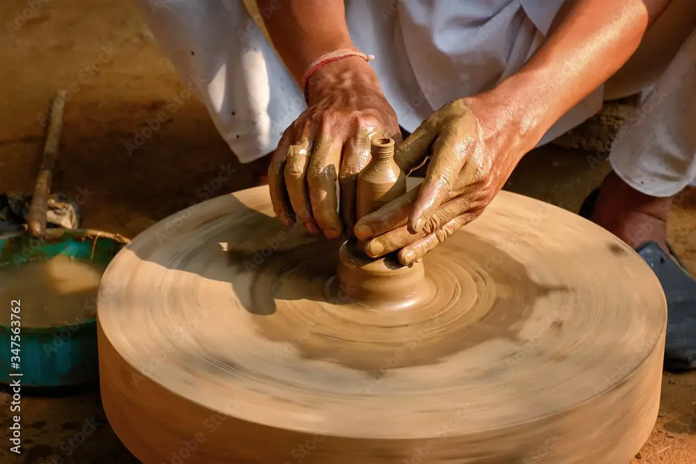 a potter shaping clay on a traditional pottery wheel.