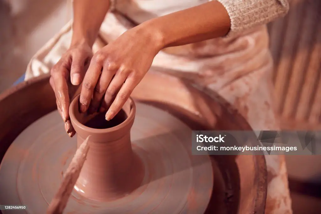 a potter shaping clay on a wheel in a ceramic studio