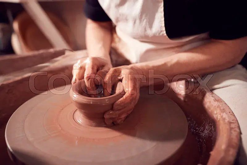 a potter shaping clay on a wheel in a studio.