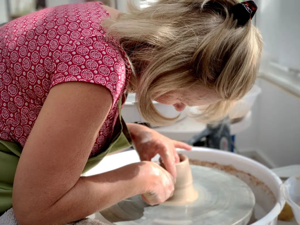 a potter throwing clay on a pottery wheel in a quiet studio.