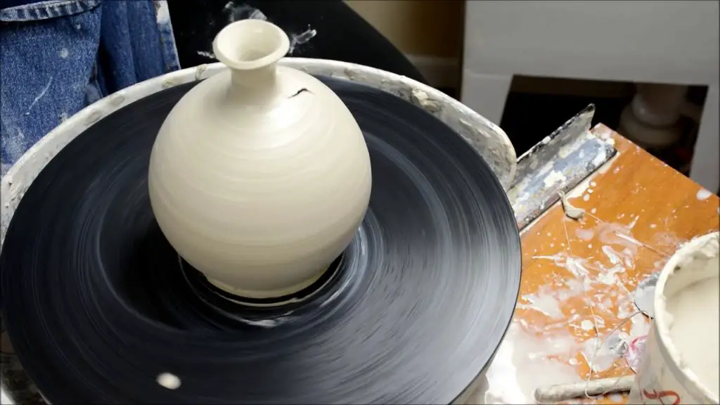 a potter using a pottery wheel to shape a vase from clay