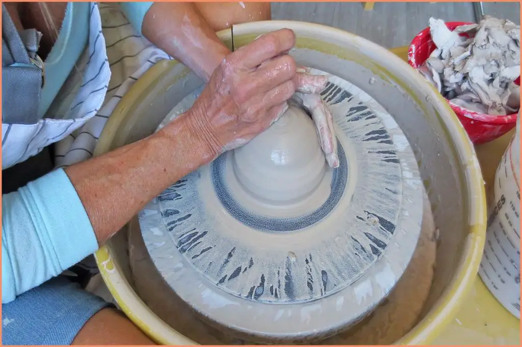 a potter wedging clay on a plaster table in preparation for throwing on the wheel.