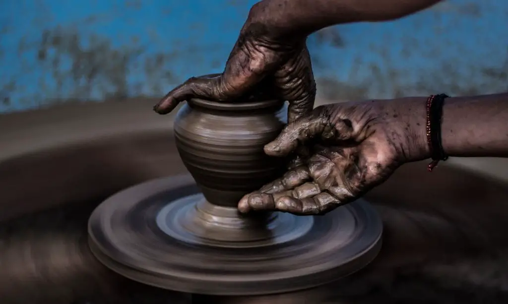 a potter working on a pottery wheel shaping a clay pot.