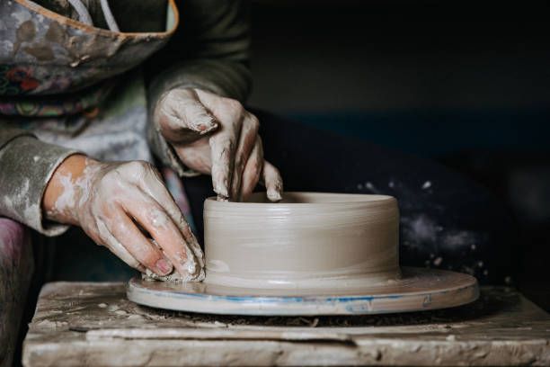 a potter working on a pottery wheel shaping clay.