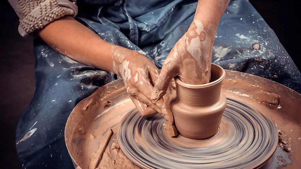 a potter working on a wheel, focused on crafting a new piece of pottery