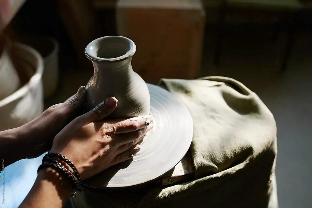 a potter working on a wheel throwing a delicate porcelain vase