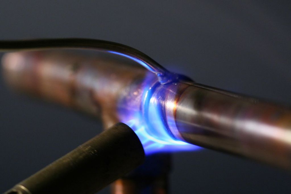 a propane torch being used to solder copper pipes.