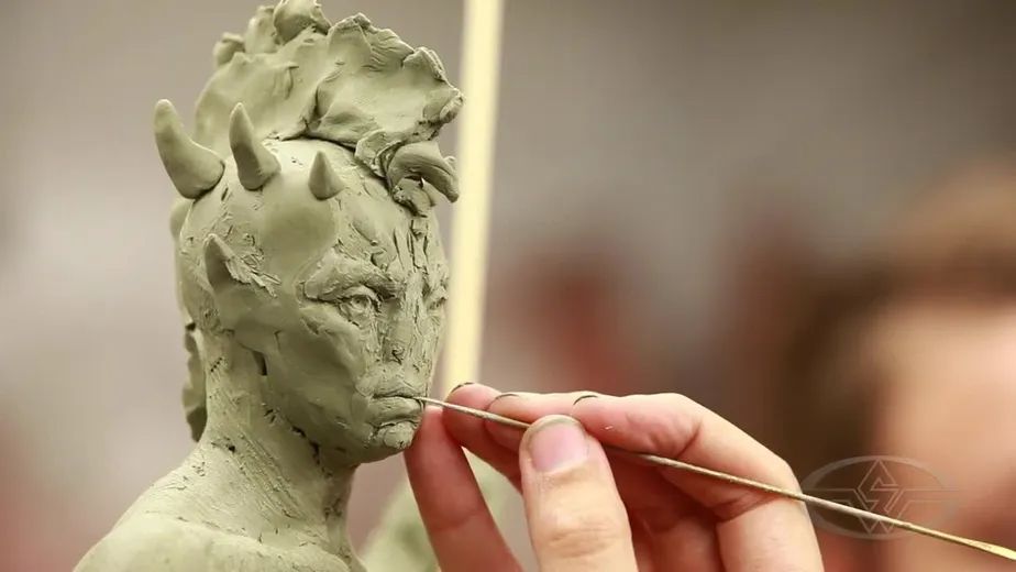 a sculptor working on a clay figure, refining facial details
