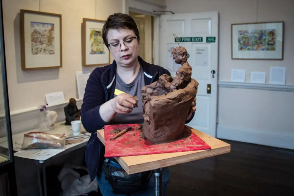 a sculptor working on a human figure clay sculpture