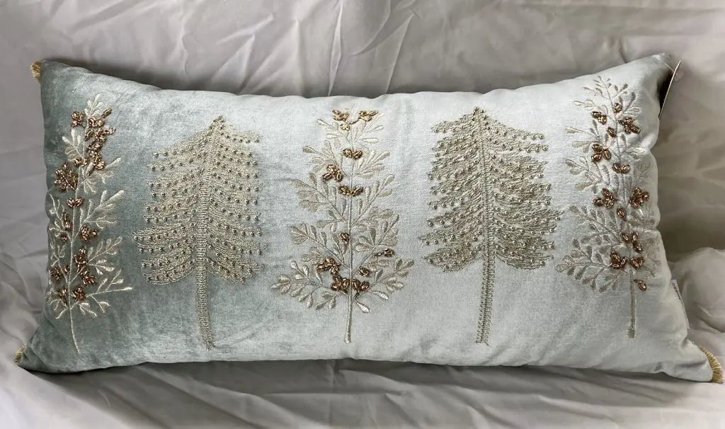 a soft decorative pillow with intricate beadwork and embroidery on a table.