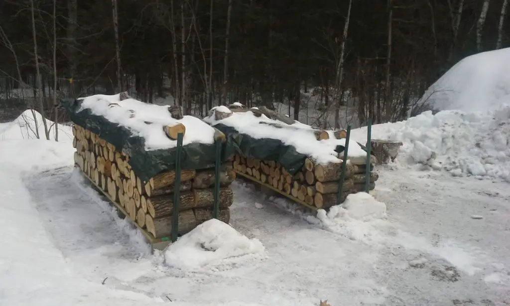 a stack of winter firewood with snow on the ground.