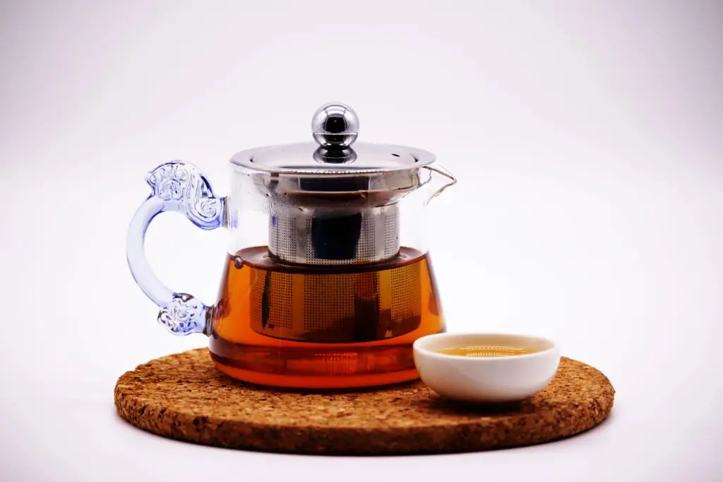 a stainless steel tea infuser sitting in a teacup with steaming hot tea