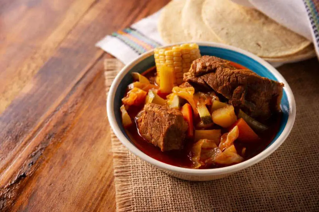 a traditional mexican olla cooking pot with a stew inside.