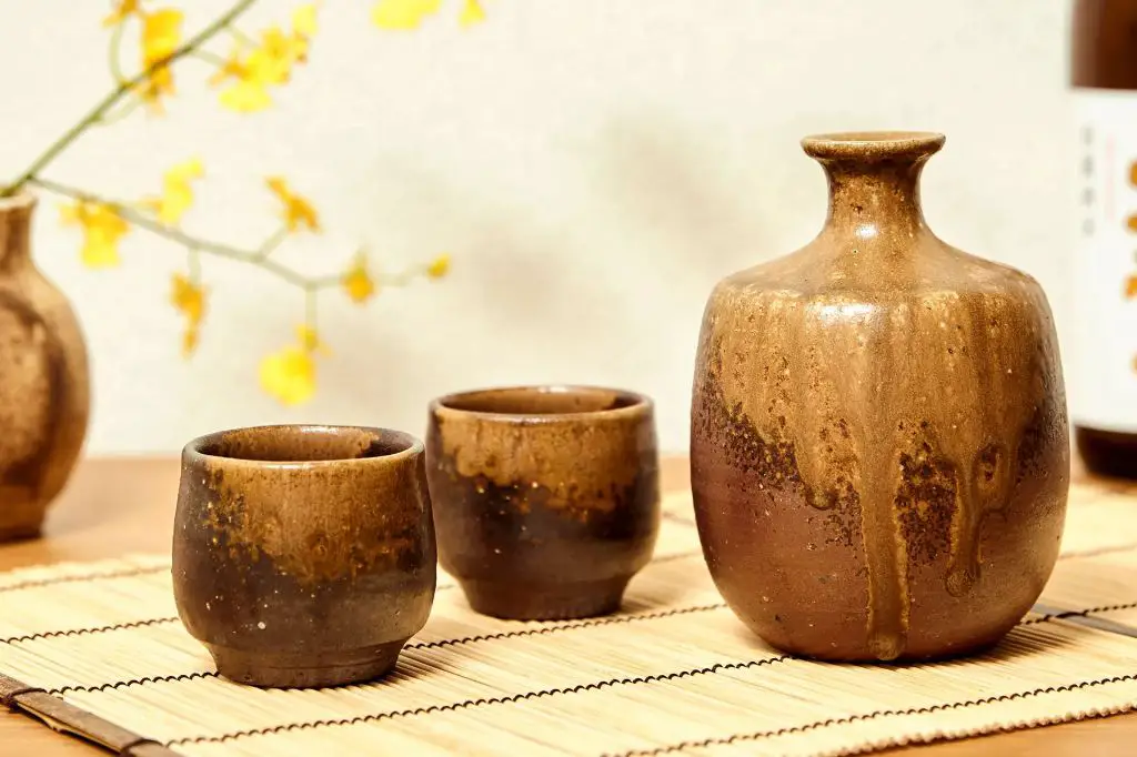 a variety of beautifully glazed pottery mugs sitting on a kitchen counter, representing the artistry, durability, and variety of styles possible with ceramic drinkware.