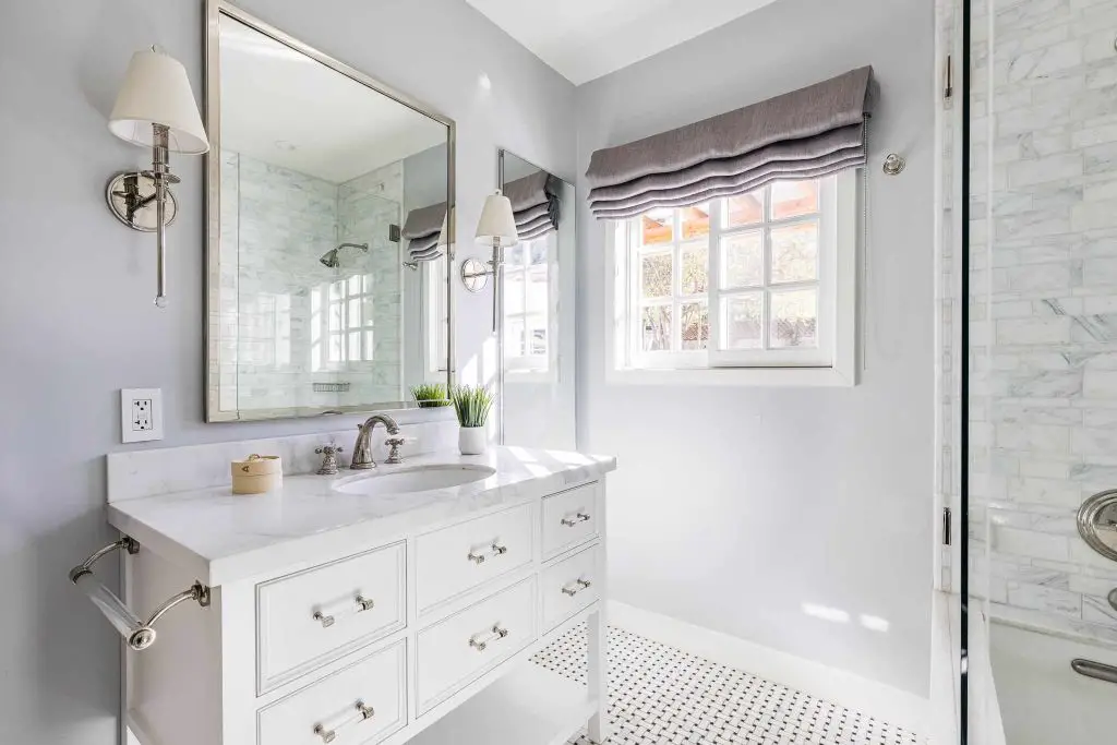 a white mirror frame complements a bright, spacious bathroom with neutral walls and tiles