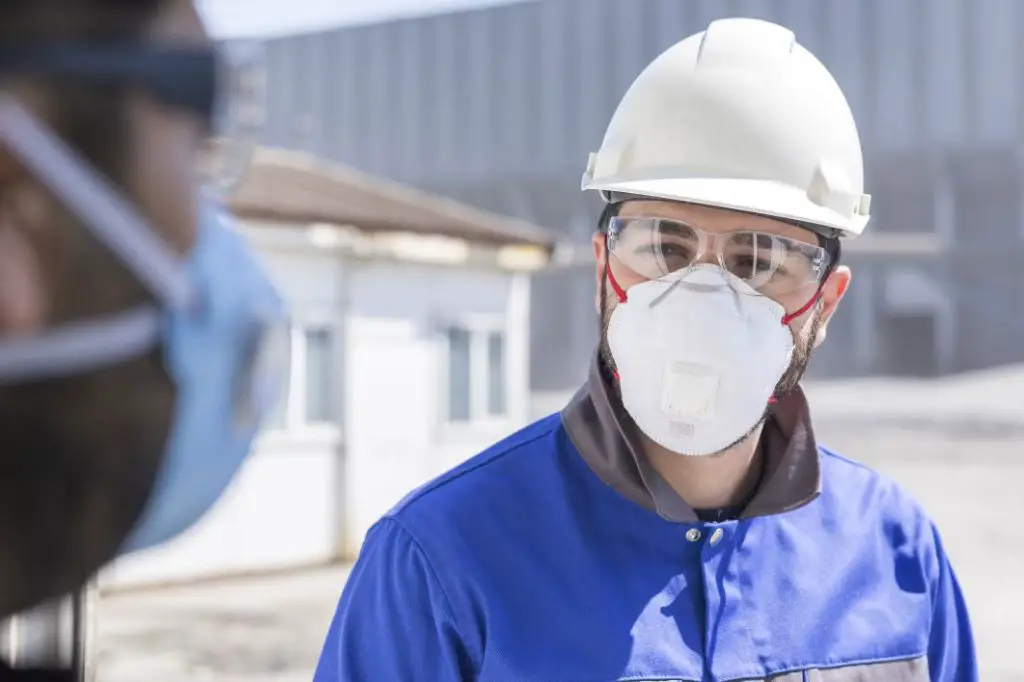 a worker wearing protective equipment while handling ceramic fiber insulation.