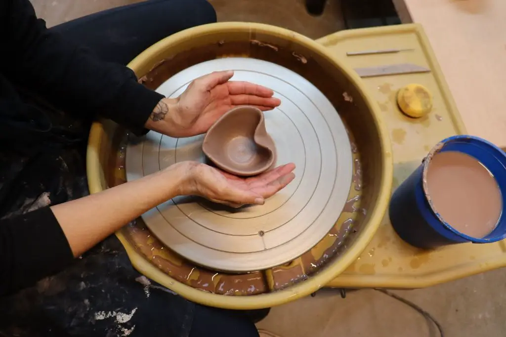 an artist decorating a ceramic bowl in the costa mesa ceramics studio