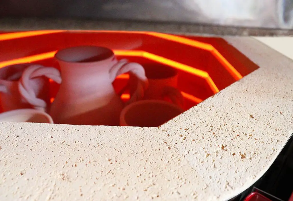 an electric kiln being used to fire pottery, generating significant heat