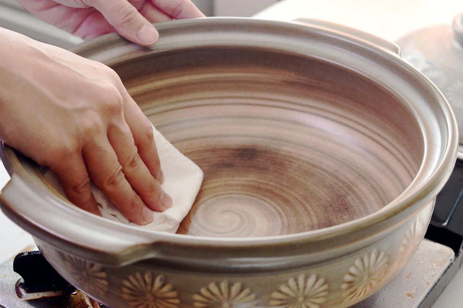 an image showing someone gently scrubbing a clay pot