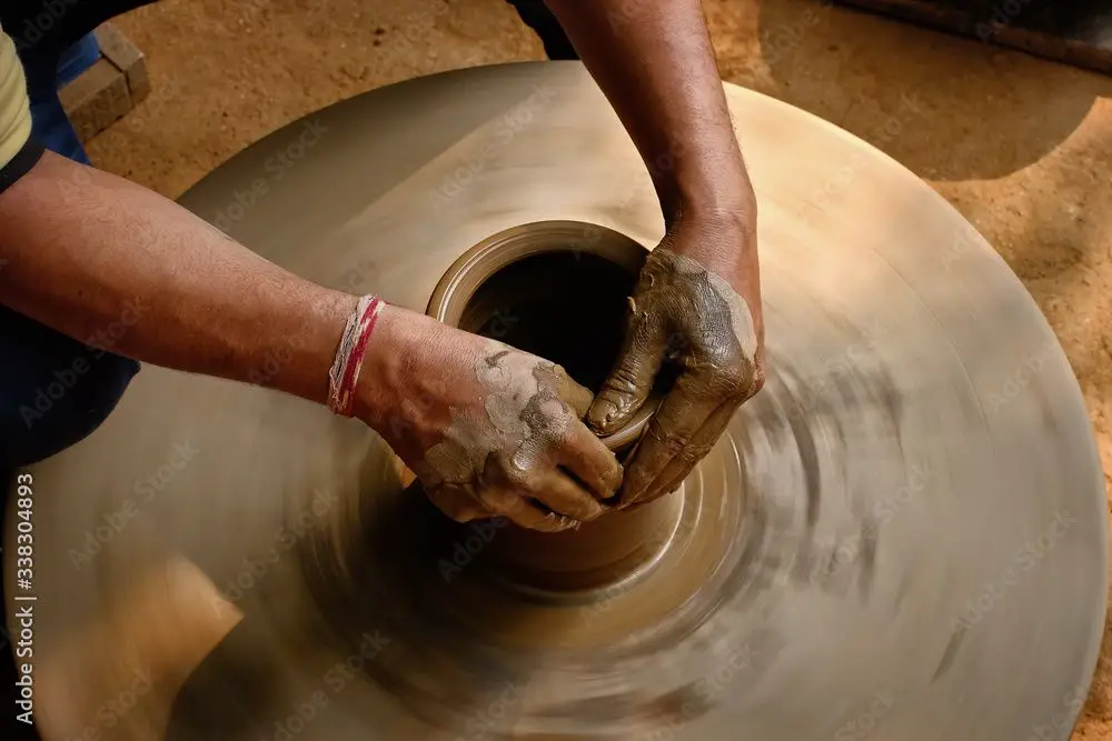 an indian potter shaping clay pots by hand