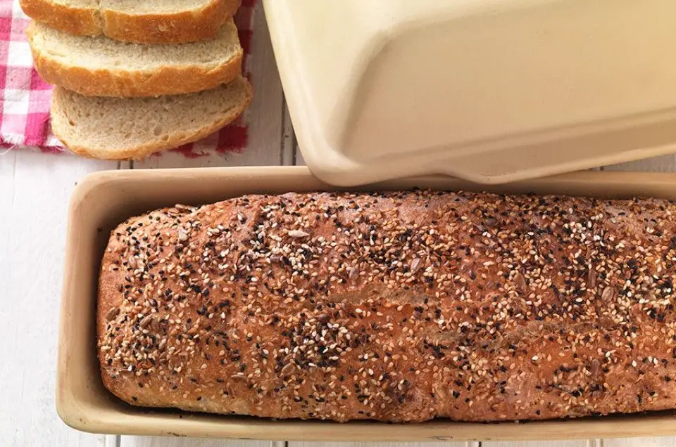 baker removing freshly baked bread loaf from a ceramic pan