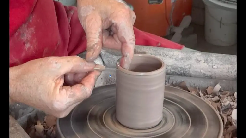 ceramic artist using a needle tool on a clay pot