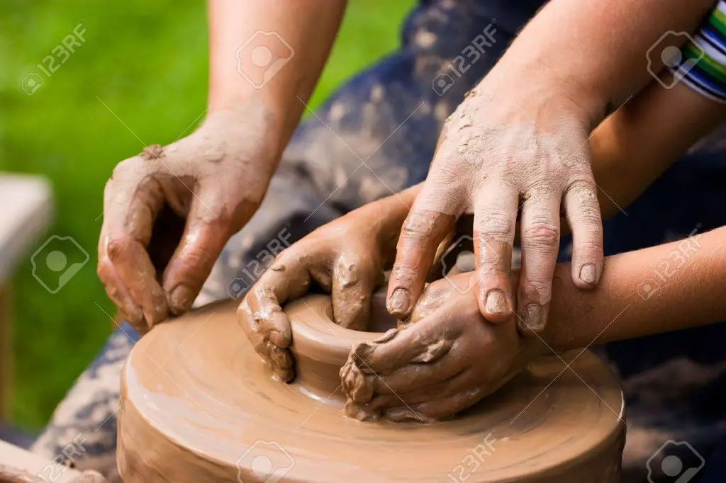 child using a pottery wheel with assistance