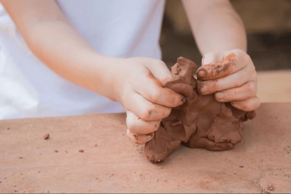 child's hands shaping clay into creative sculpture