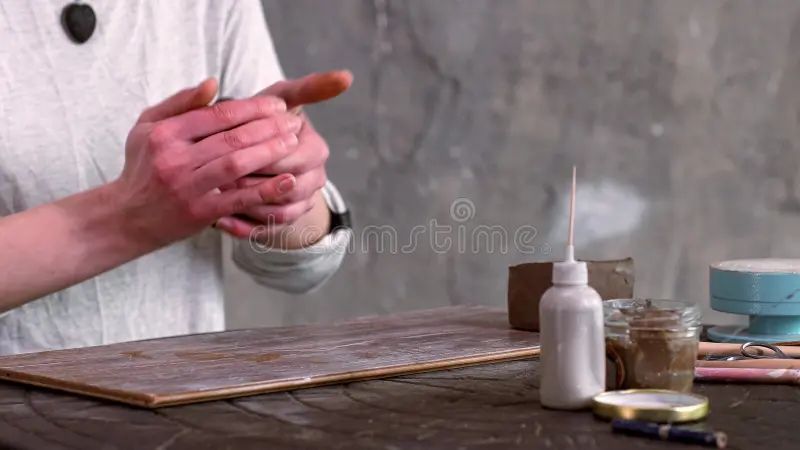 close up image of an artist's hands using loop tools to smooth and shape clay